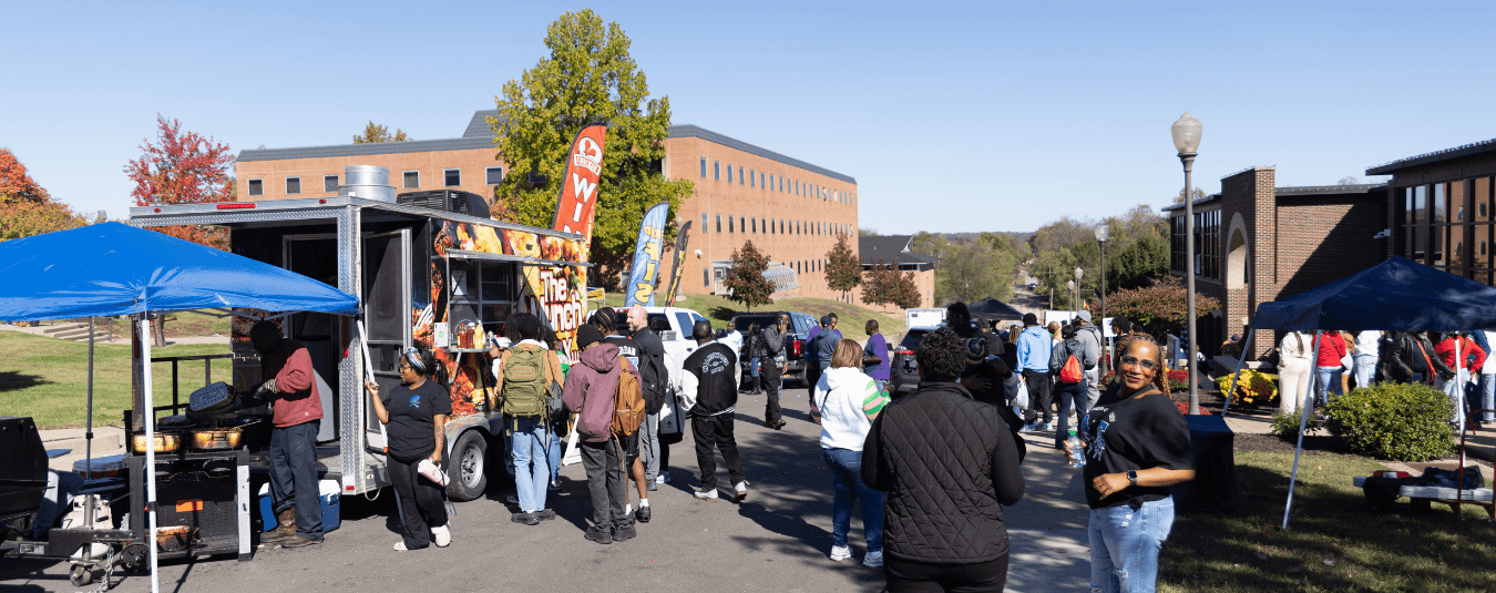 Students, faculty and staff gather along a campus roadway as food trucks serve attendees during an outdoor event at Lincoln University of Missouri