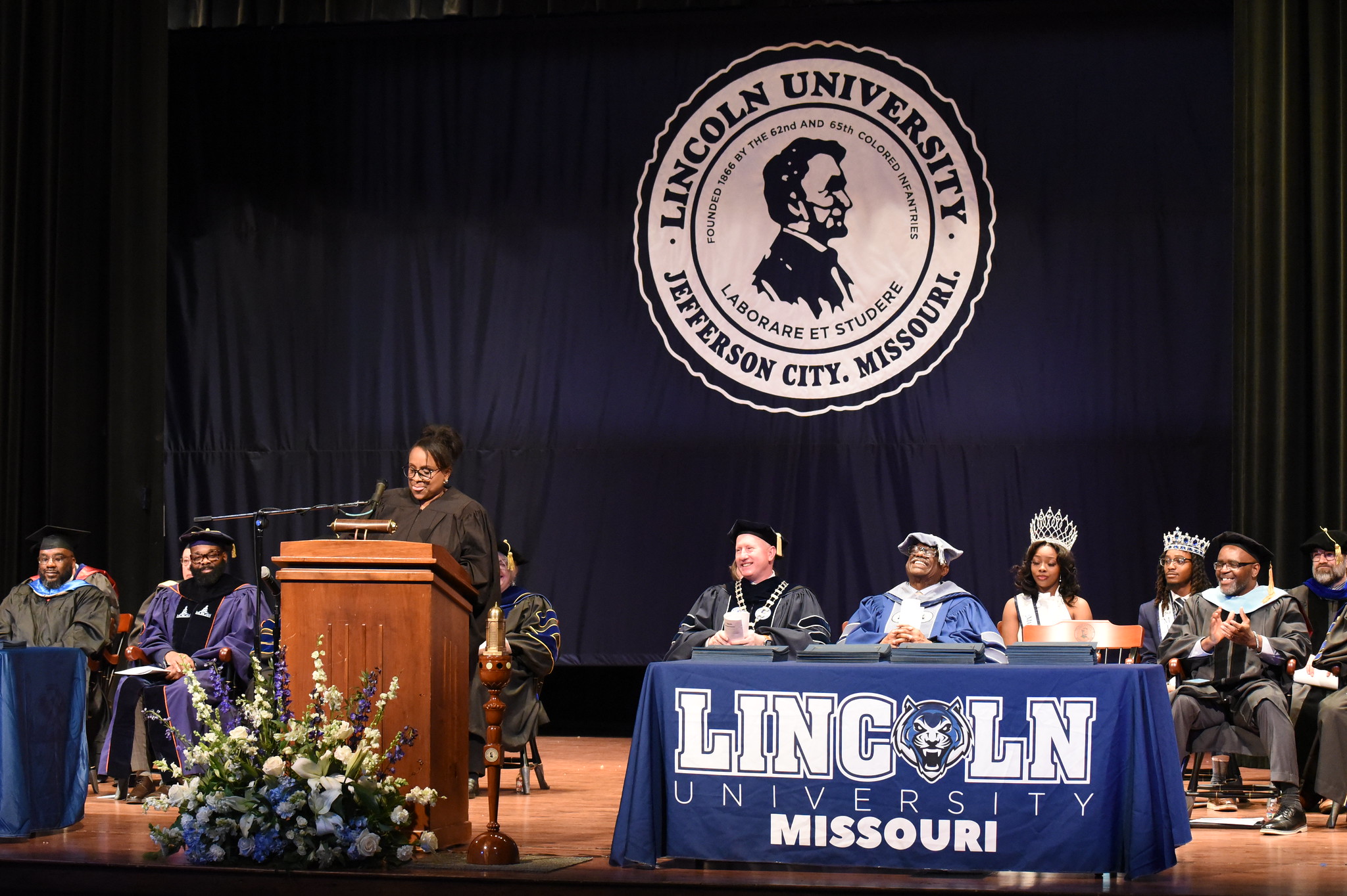 Rhonda Lewis-Allen stands behind a podium on a stage while giving her speech at the 2025 Honors Convocation ceremony.