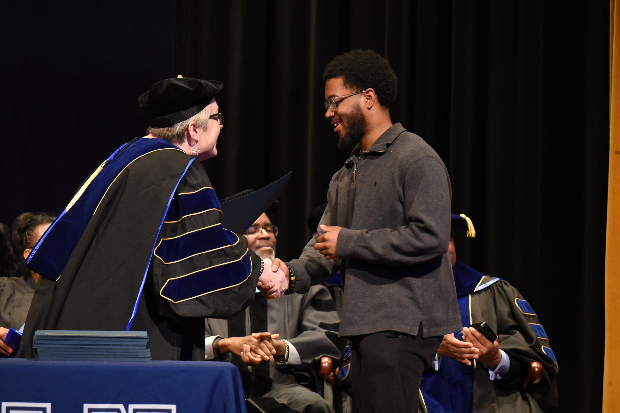 A Lincoln University of Missouri student shakes hands with his professor on stage during the 2025 Honors Convocation. 