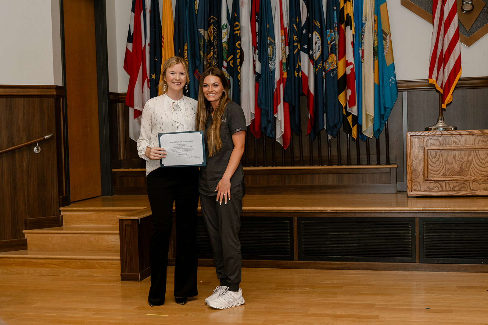 A Lincoln University of Missouri Fort Leonard Wood nursing graduate stands on stage with a faculty member whille holding a certificate.