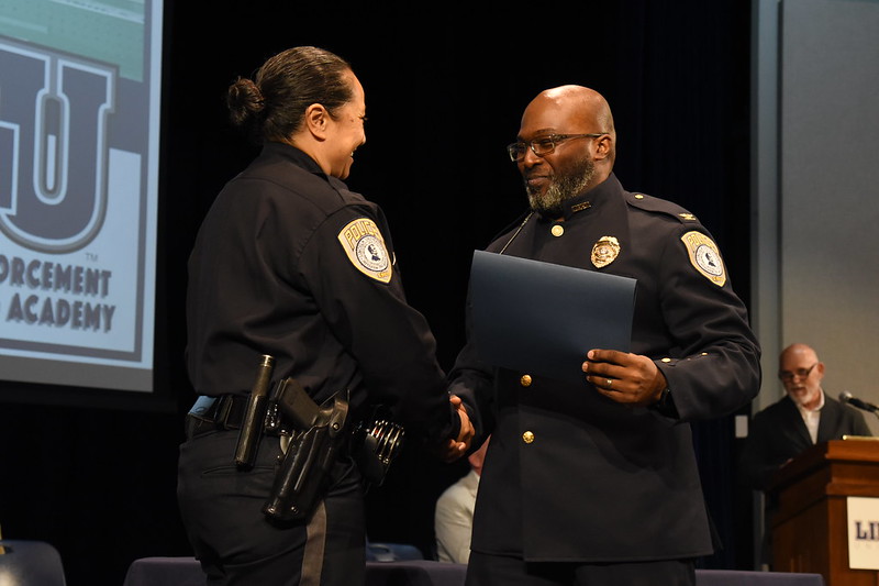 Lincoln University officer congratulates a graduate with a handshake and certificate during 2025 Law Enforcement Academy ceremony.