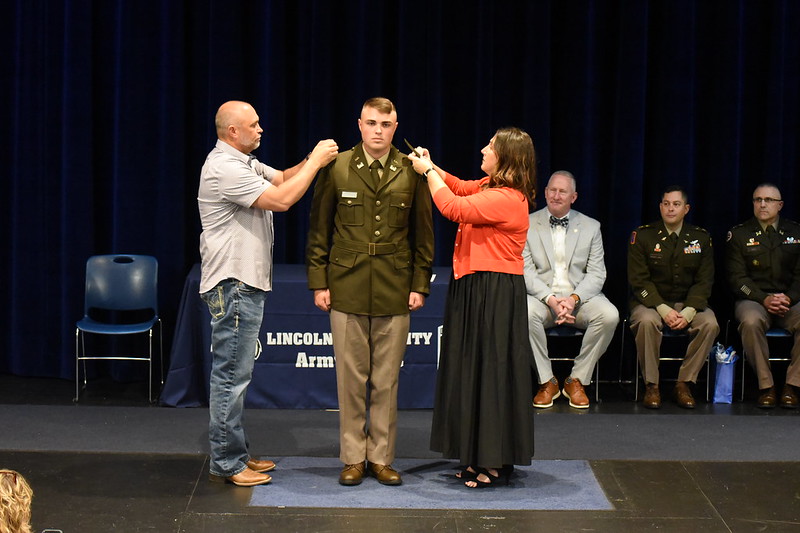 Cadet Blake Fischer's parents pin his rank on his lapel during his 2025 spring commissioning ceremony.