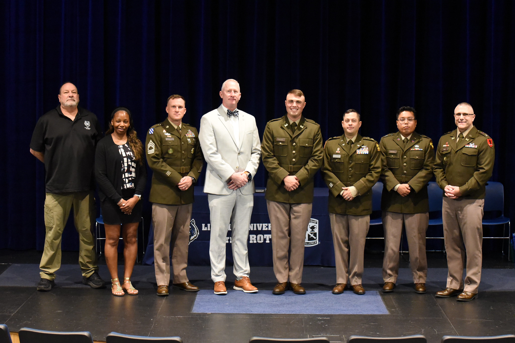 Lincoln University of Missouri ROTC staff members stand in a line on stand with Cadet Blake Fischer for a group photo.