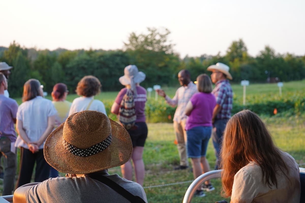 Two women in the foreground sit watching a group of people in the background.