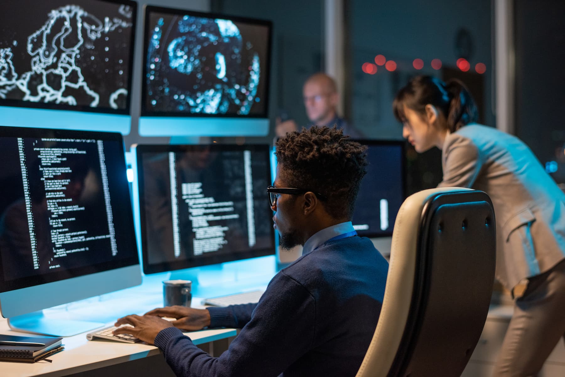 Image of a man and women working at computers focusing on cybersecurity.