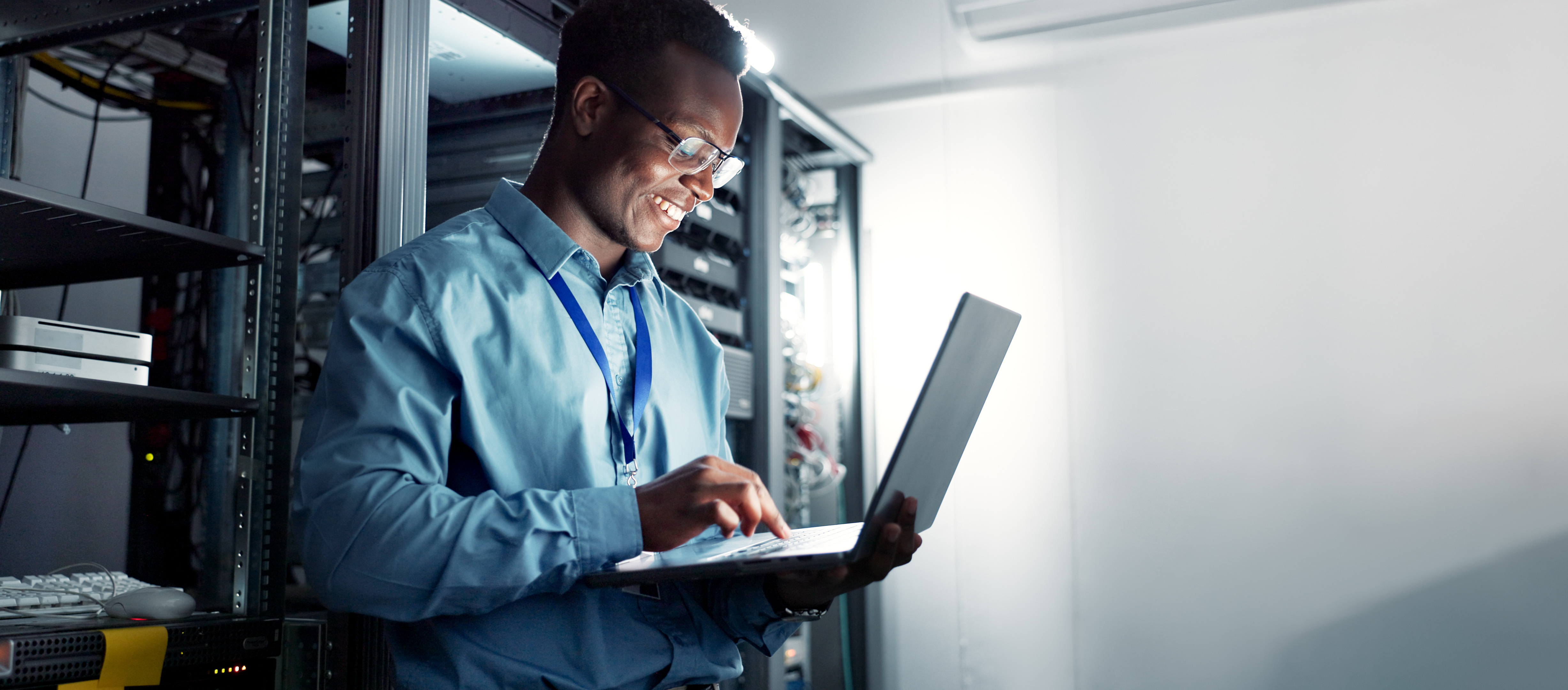Image of a cybersecurity professional working on a laptop in a server room.