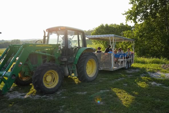 John Deere tractor pulling tram of visitors at Busby Farm Field Day event