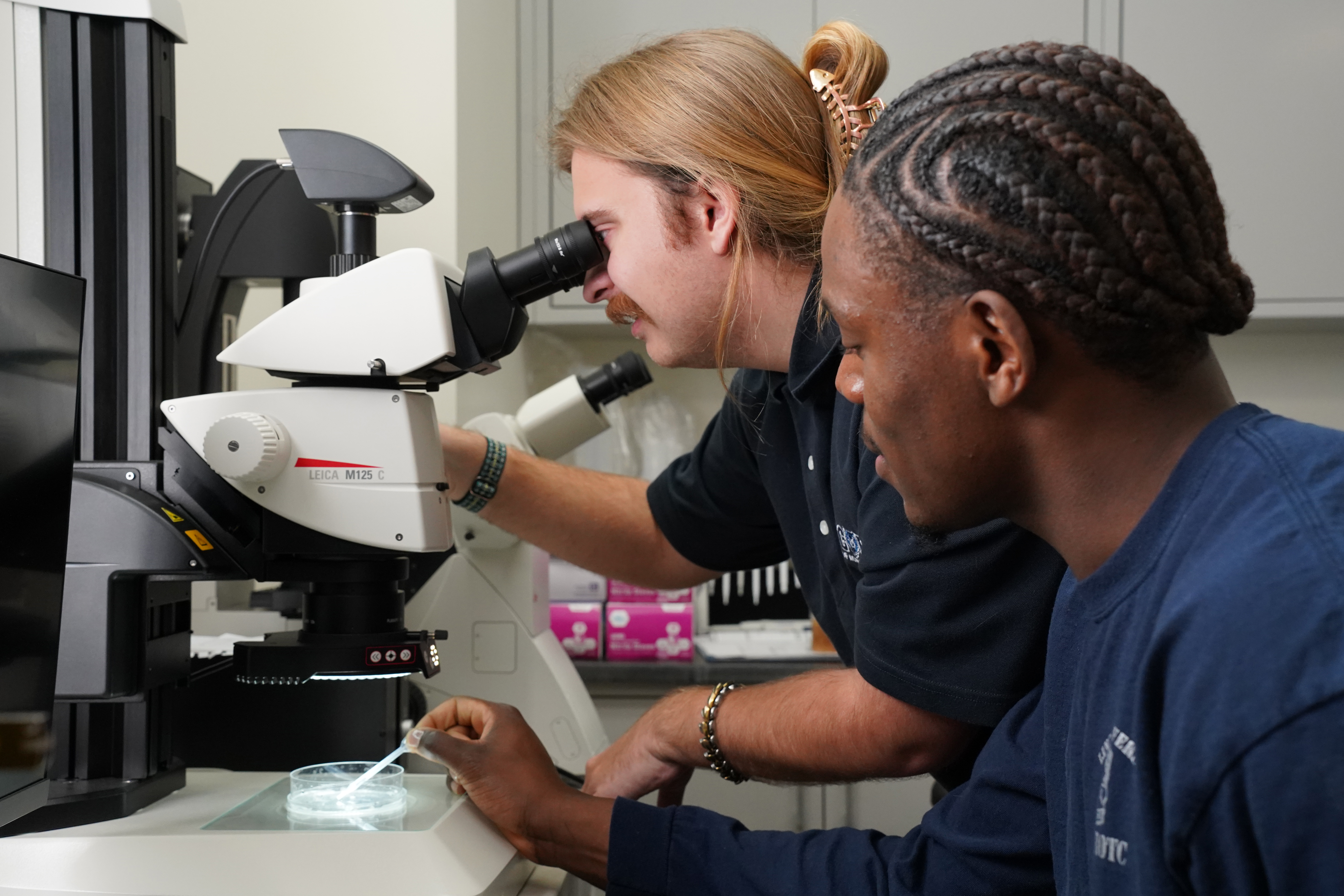 Image of Lincoln University interns working in the science department with a microscope.