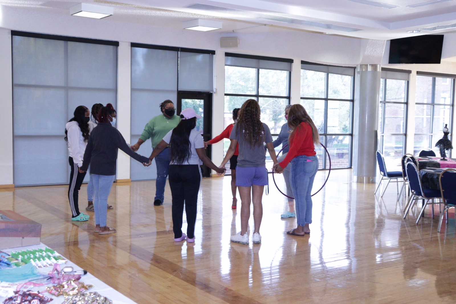 depiction of During this ice breaker activity, attendees were asked to move the hula hoop from one end of the circle to the other without unlocking their hands. The purpose was to build community, trust, and camaraderie among the women while also embracing the importance of communication.