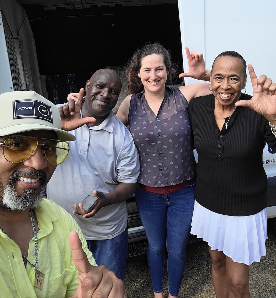 Four people pose for a photo while displaying an "L" with their hands for Lincoln University.