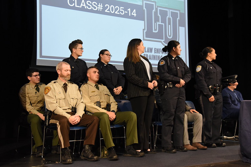Members of Lincoln University Law Enforcement Training Academy Class #2025-14 seated and standing on stage during ceremony