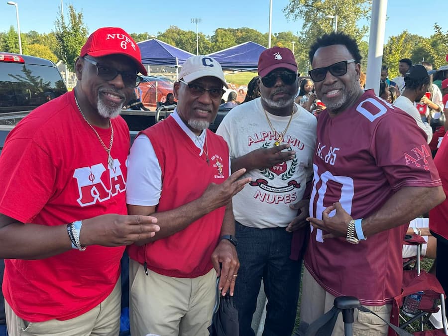 Four Lincoln University of Missouir male alumni stand in a line posing for a photo at a Homecoming alumni event.