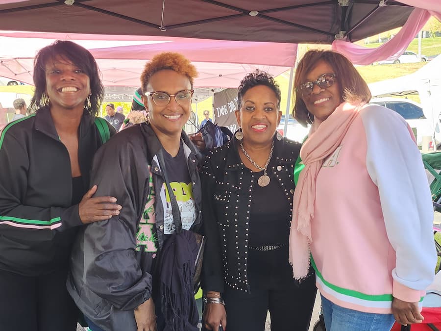 Four female Lincoln University of Missouri alumni members stand in a line posing for a photo at an alumni Homecoming event.