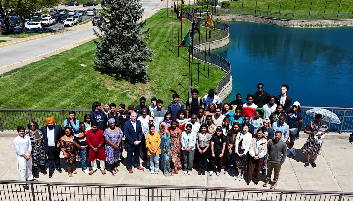 Drone photo of Lincoln University of Missouri international students posing for a group photo outside with grass and a pond behind them.