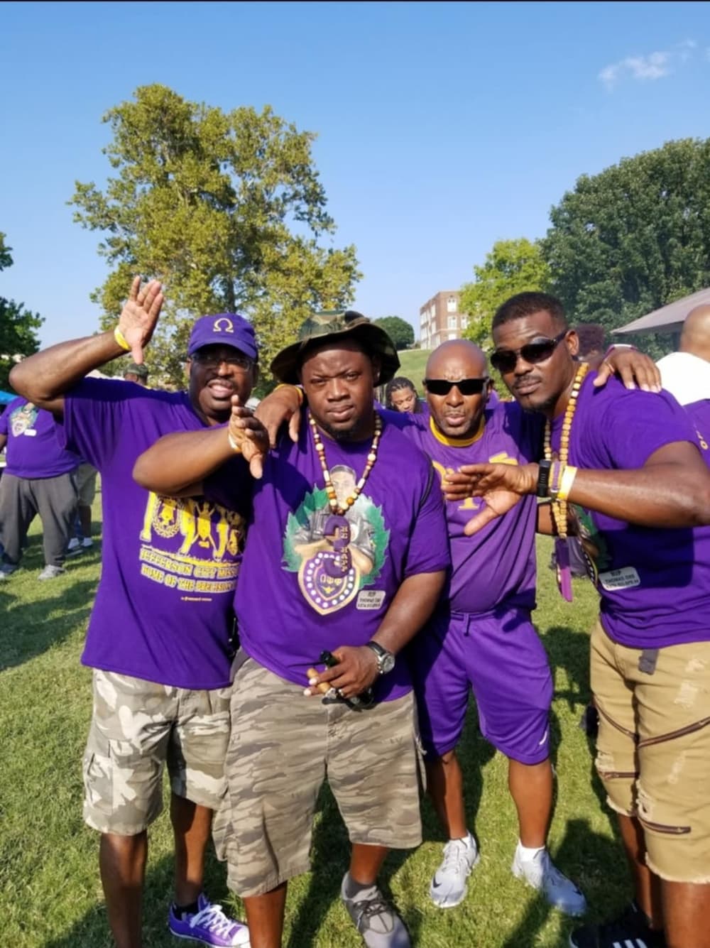 A group of four Lincoln University of Missouri alumni dressed in purple shirts pose for a photo during a Homecoming tailgate.