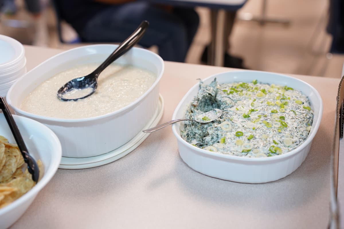 Two serving dishes sit on a counter. One holds dip, the other pudding.