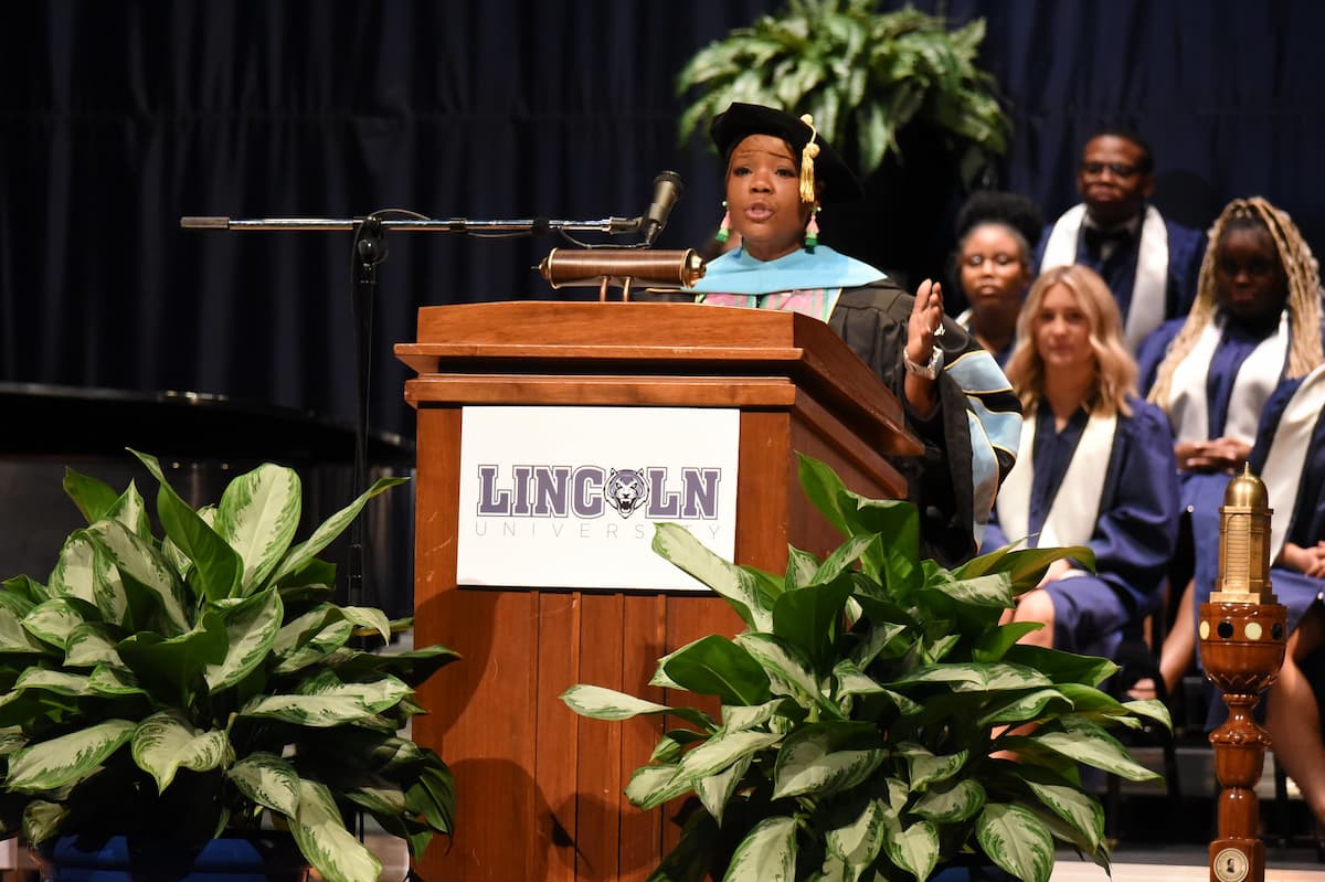 Opening Convcation keynote speaker Treaka Young stands behind the podium while on stage and addresses students.