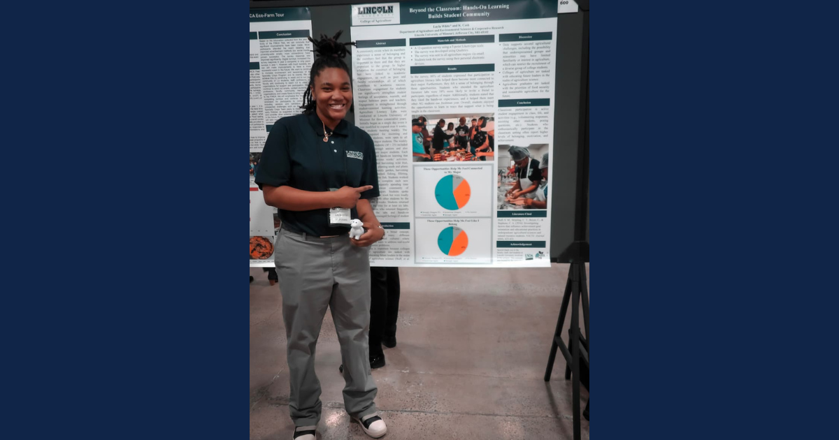 A young woman stands smiling in front of a research poster.