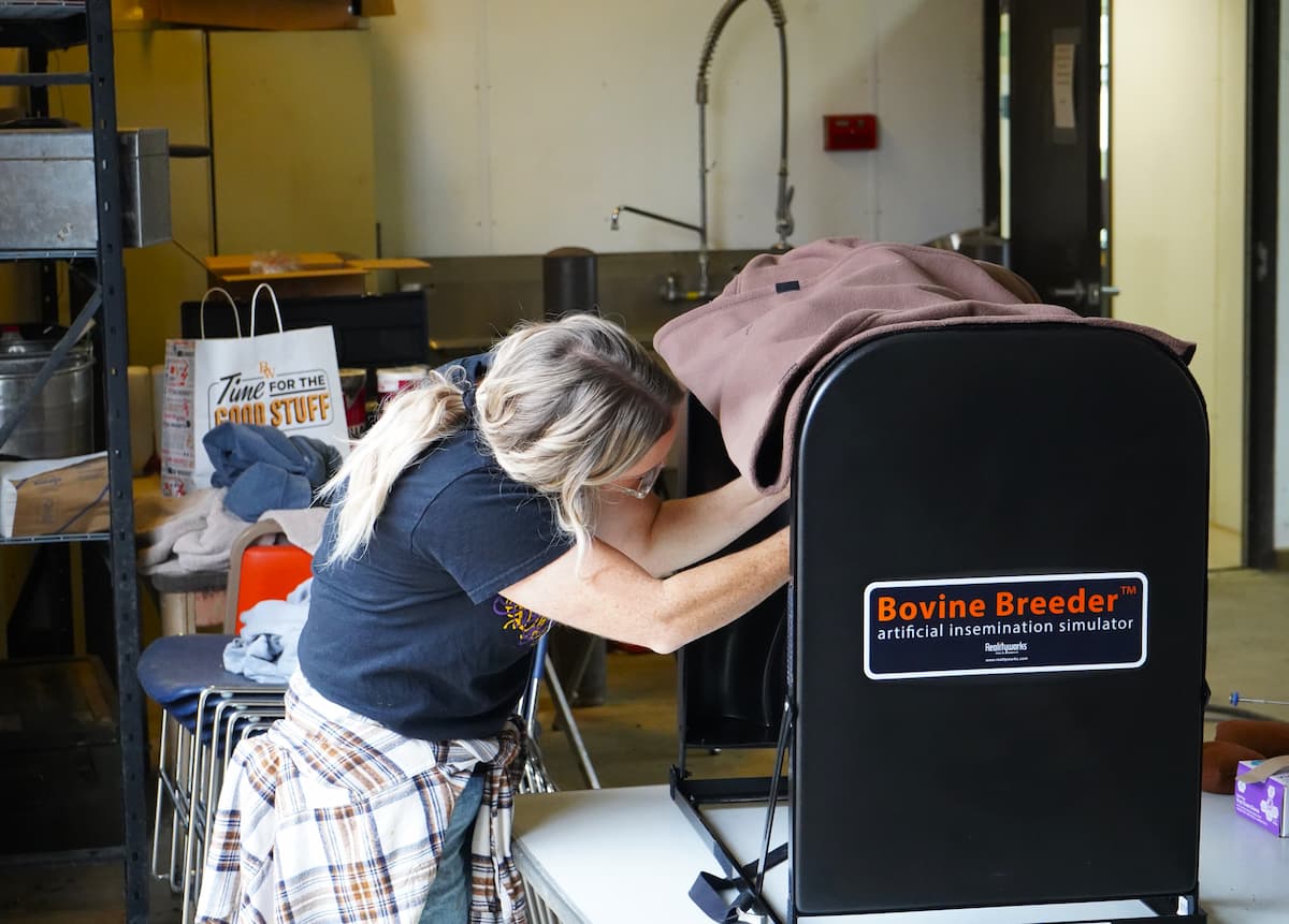 An attendee tries to find the cervix opening using the artificial insemination simulator.