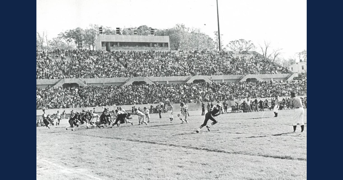 Black and white image of athletes playing football at the Dwight T. Reed Stadium.