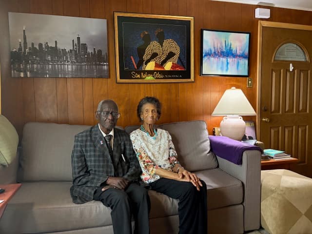 Frances and Edward Harrison sitting on a couch in their home.