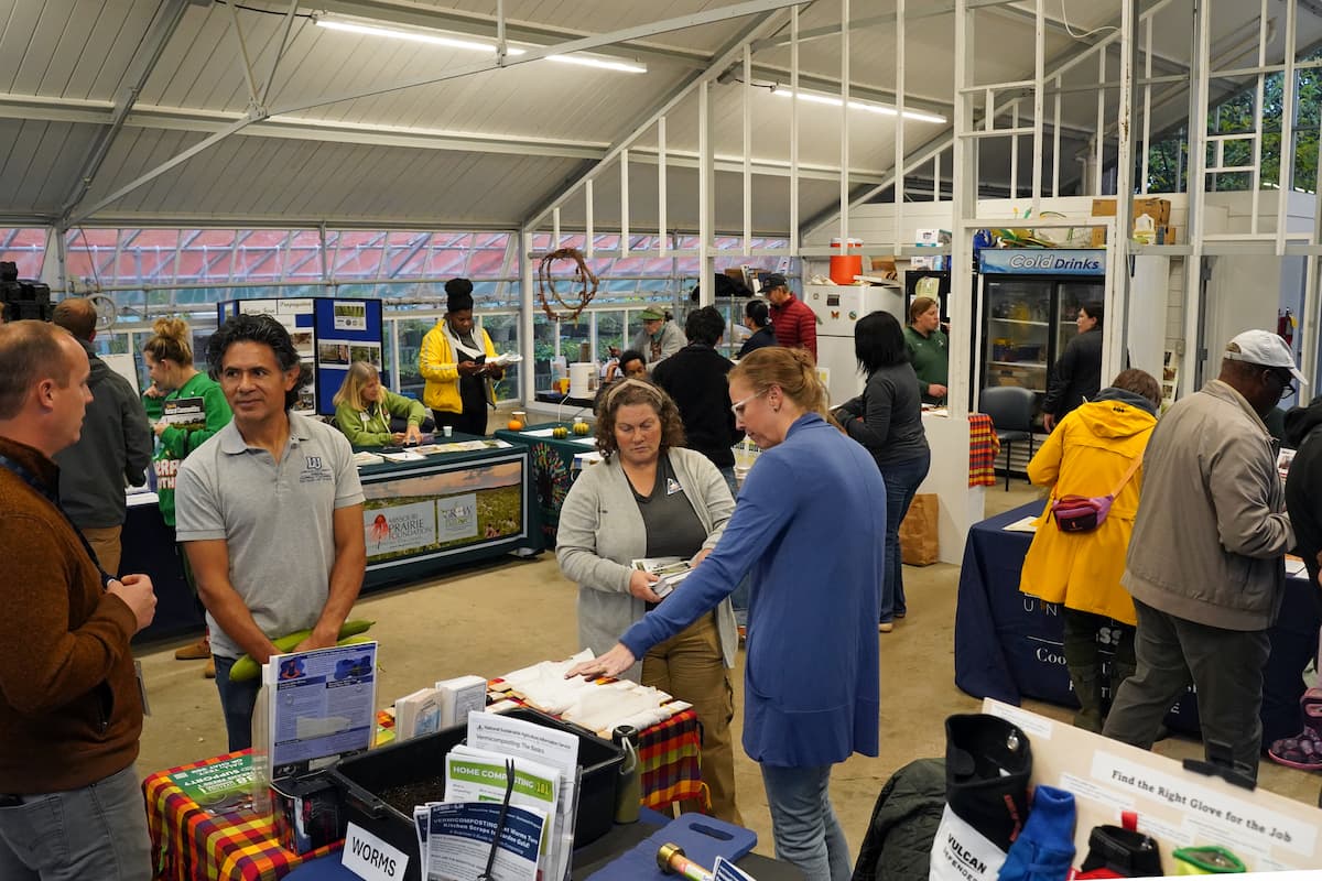 Visitors explore informational booths inside the teaching greenhouse at the Finca EcoFarm during Finca Fest.