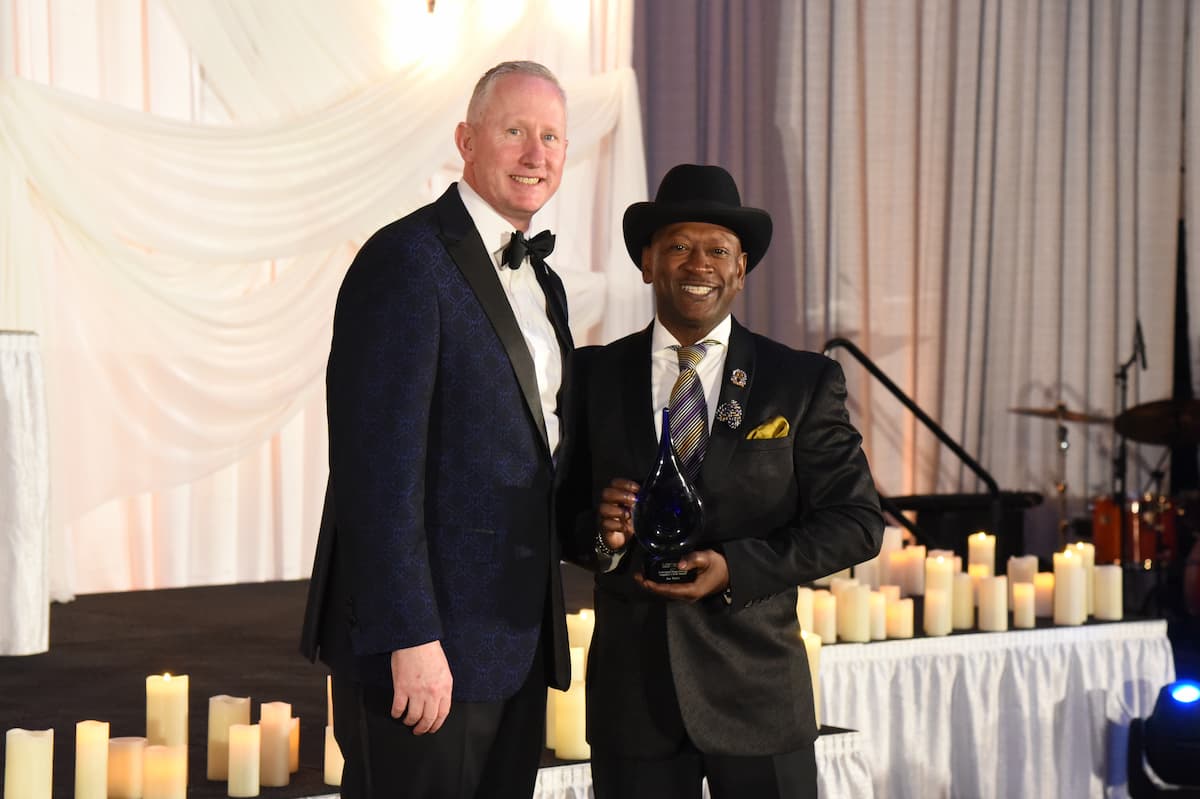 President John Moseley presents an award to a distinguished alumnus during the 2025 Masked Ball, celebrating alumni excellence and service.