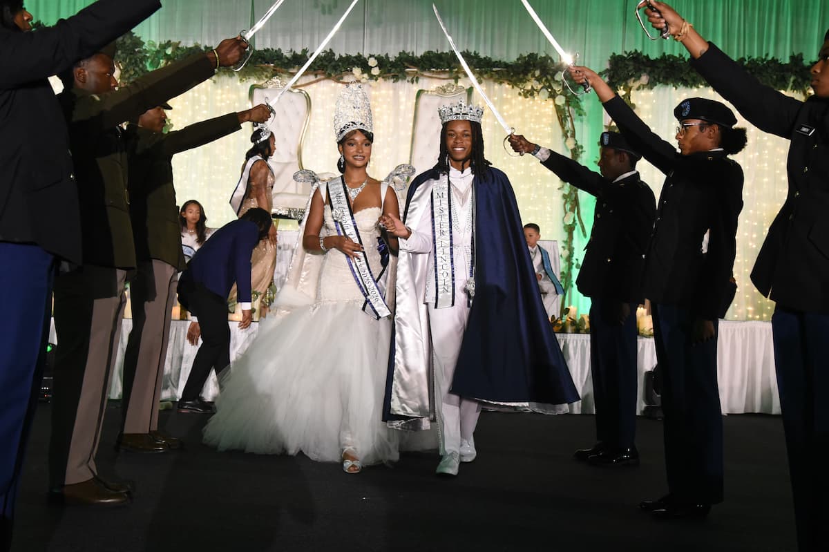 The newly crowned Mister and Miss Lincoln University walk beneath a ceremonial saber arch held by ROTC cadets.