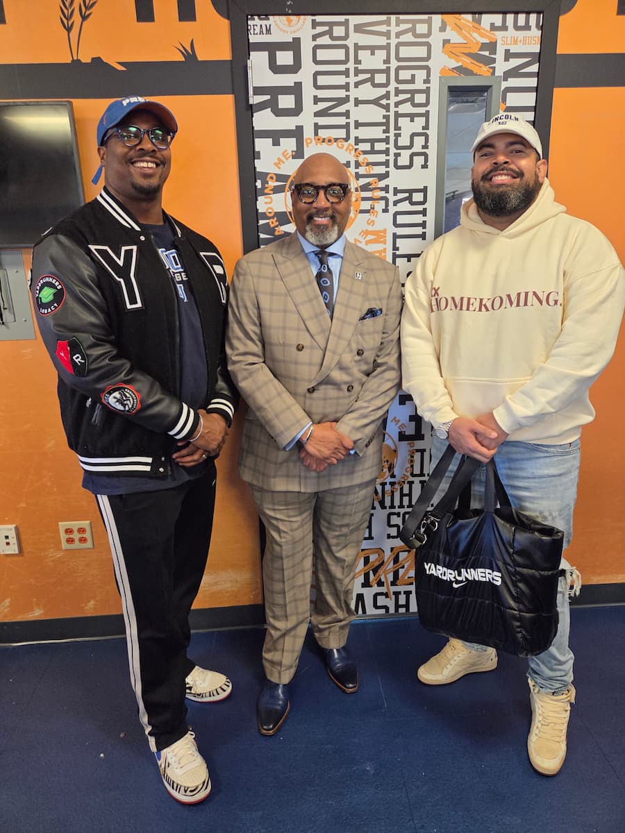 Three men stand in a row for a photograph inside of the Slim and Husky's Pizza location on Lincoln University's campus.