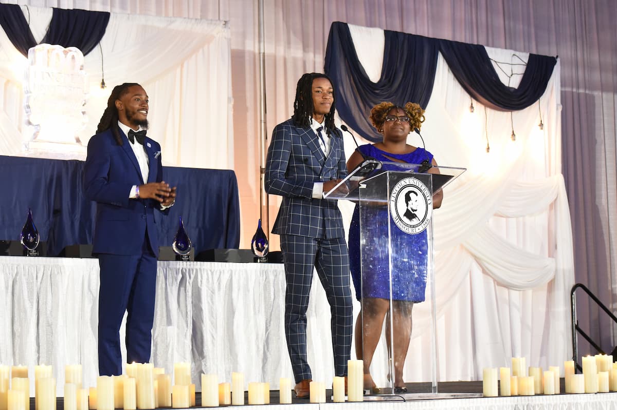 Lincoln University students serve as emcees for the Masked Ball, guiding the evening’s program from the stage decorated in navy and white.