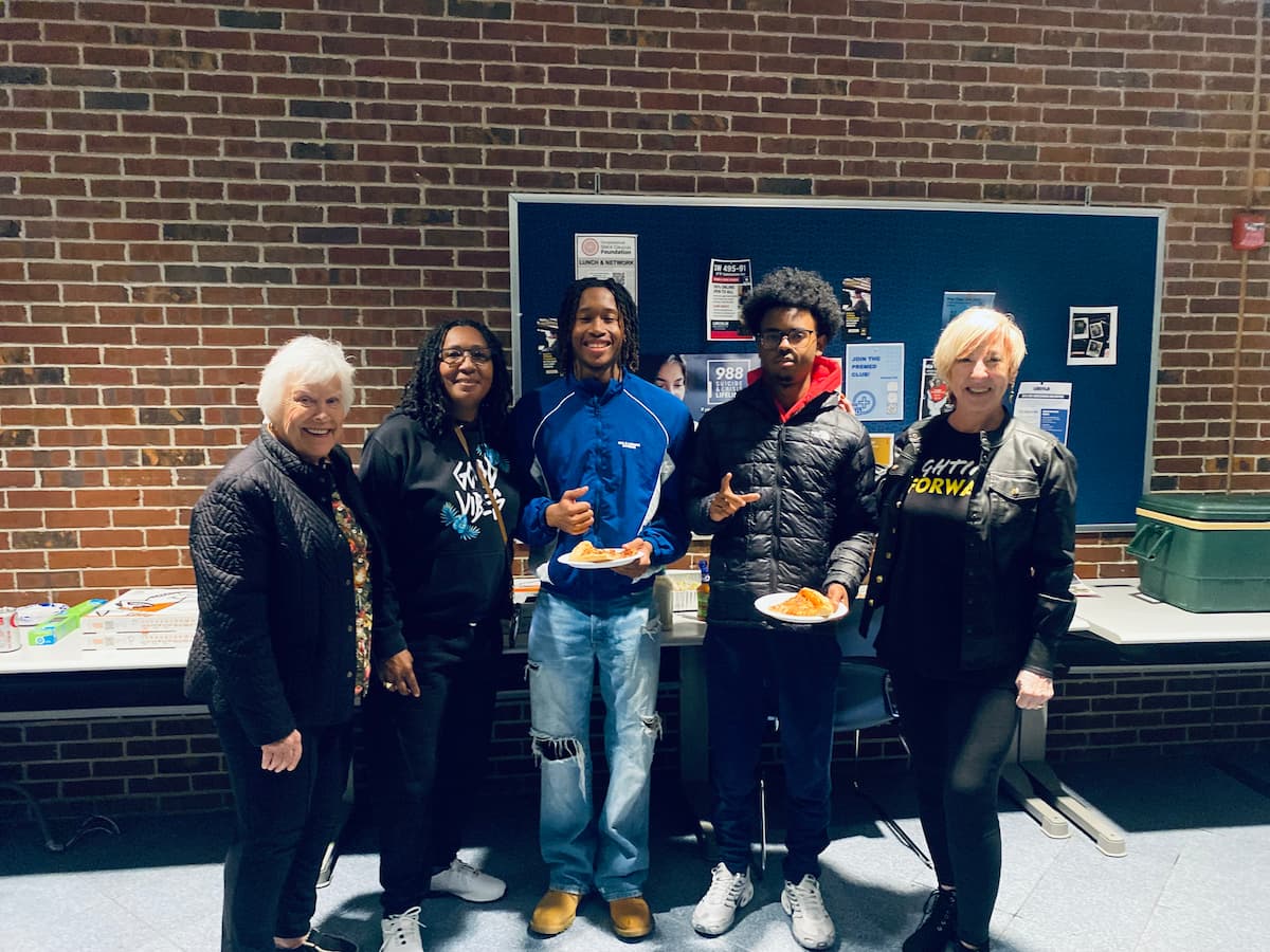 A group of LU representatives stand in a line for a photo during a pizza party.
