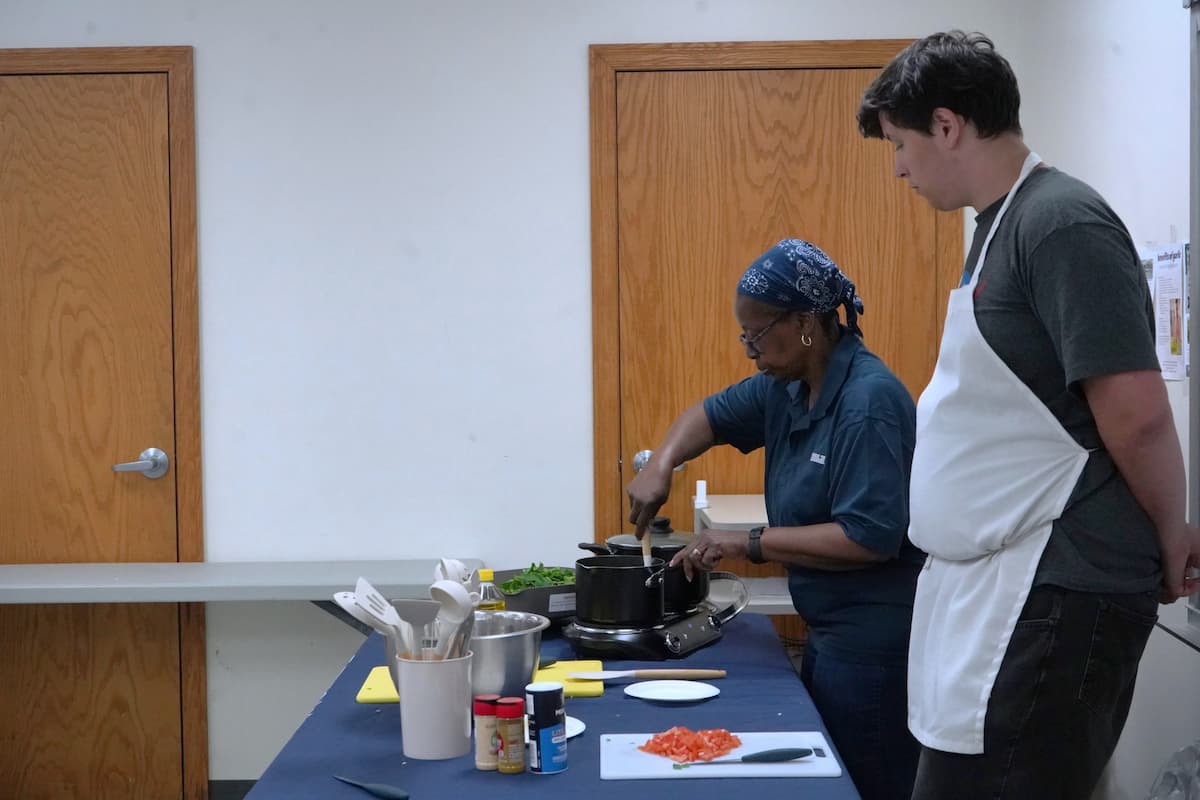 Two people cooking at a table set up like a kitchen.