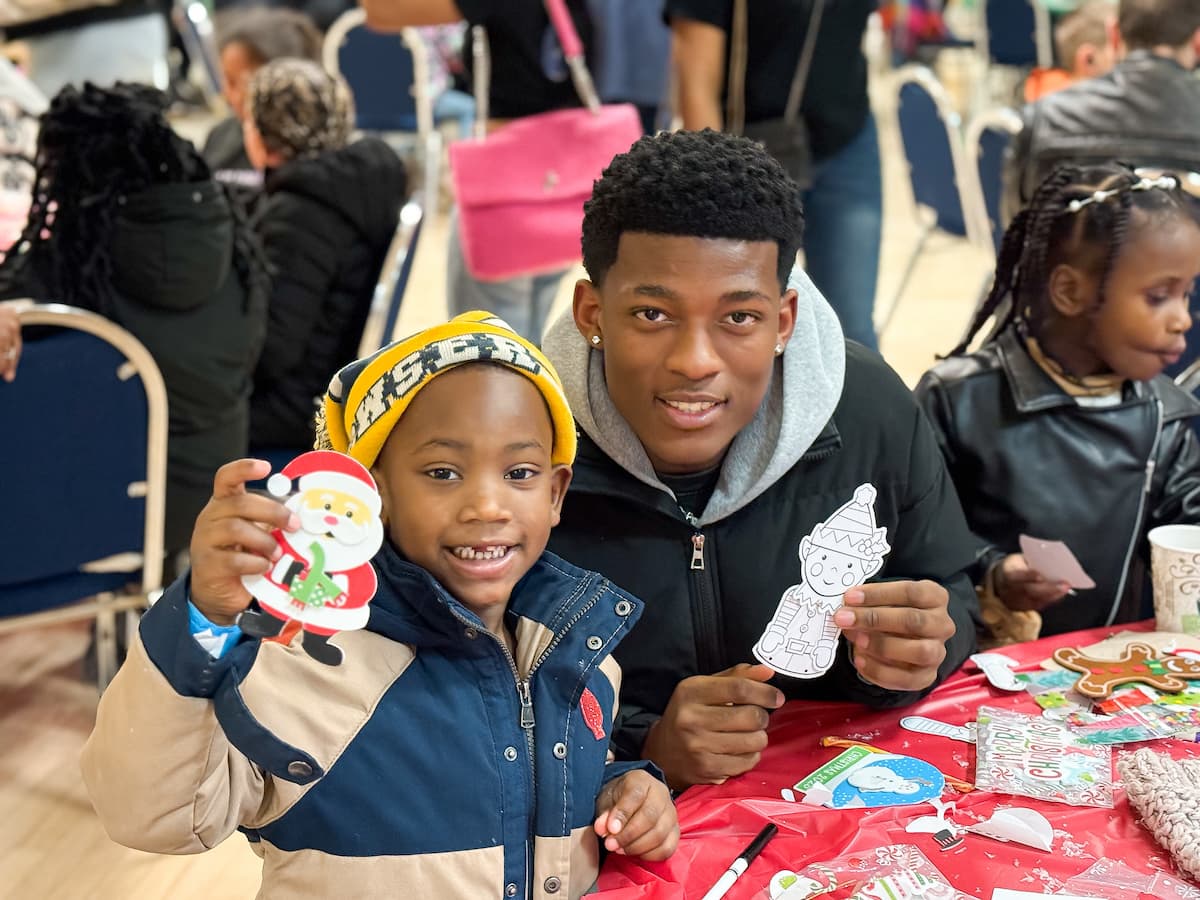 A man and a boy hold up cookies and smile at the Holiday Extravaganza 2025.