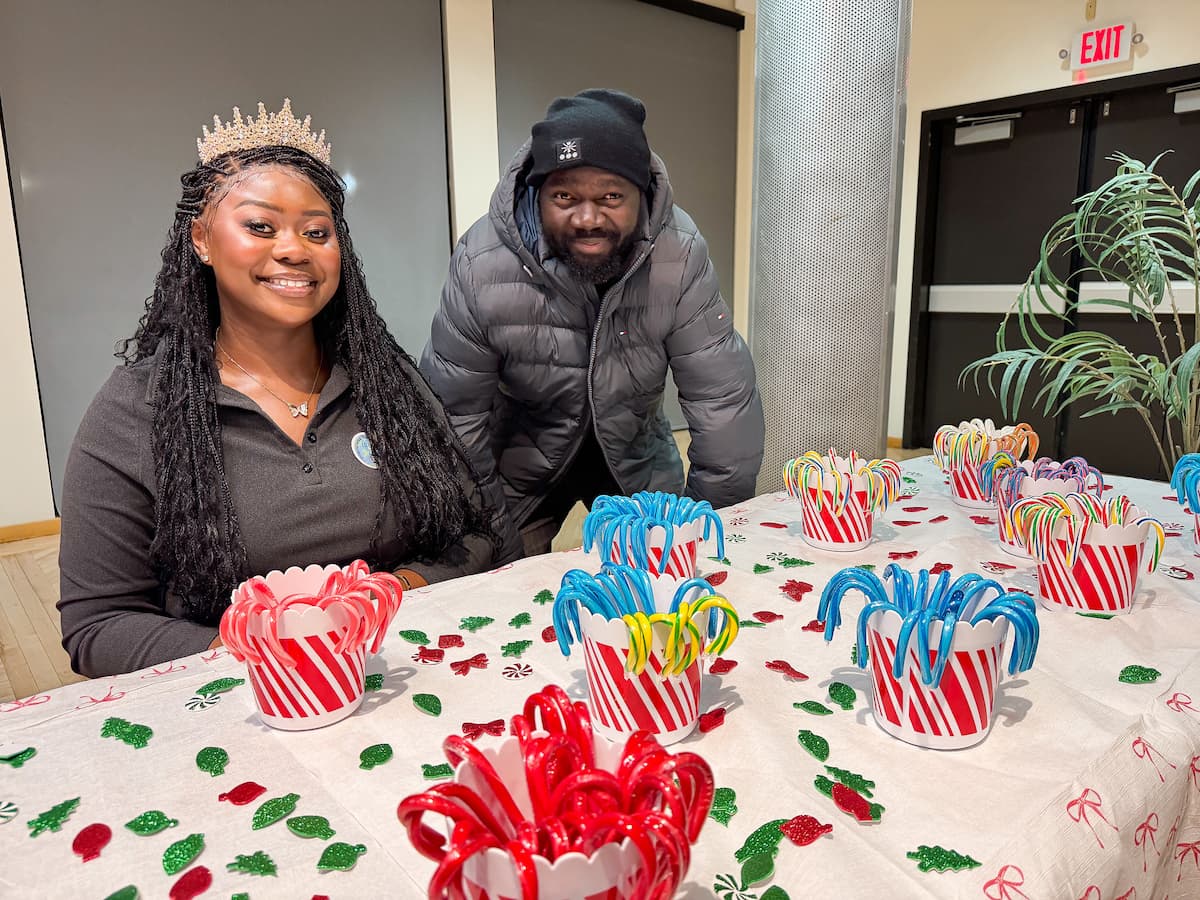Two people sit at a table while decorating cookies at the Holiday Extravaganza.