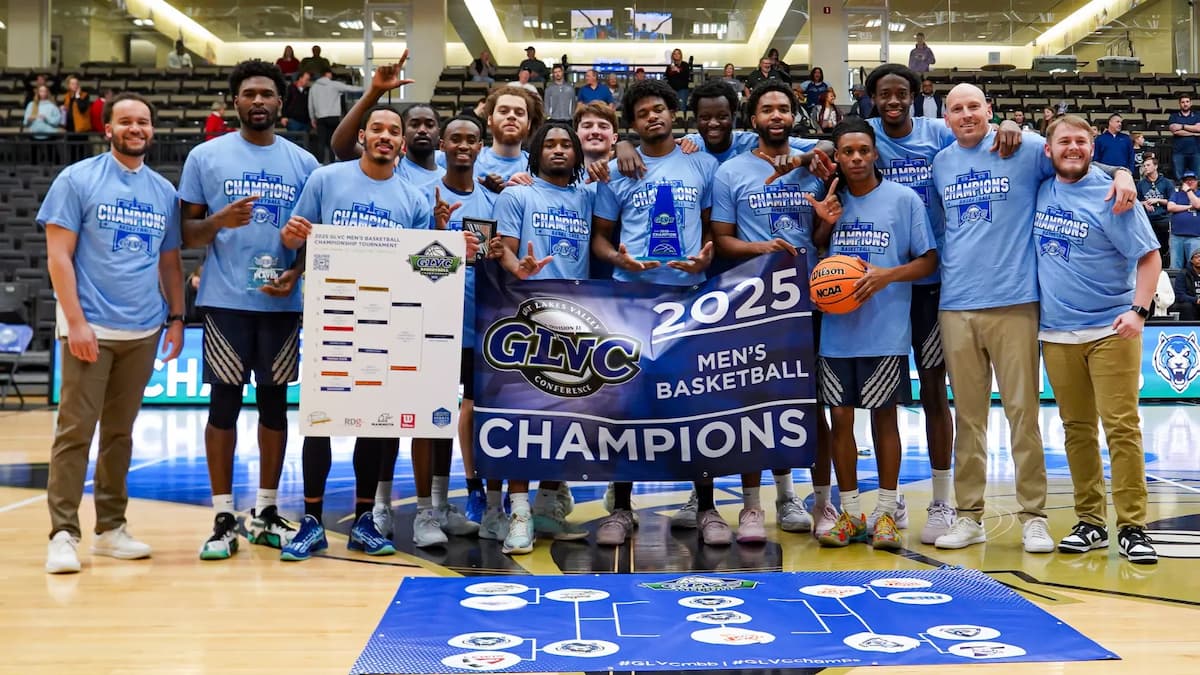 The Lincoln University of Missouri basketball team stands in the gym while wearing blue shirts and holding the GLVC championship sign.
