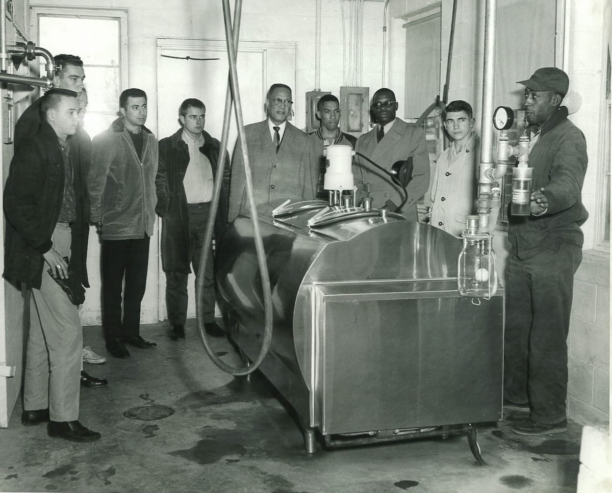 In the 1960s, James N. Freeman stands with a group of people next to a new dairy milk cooler.