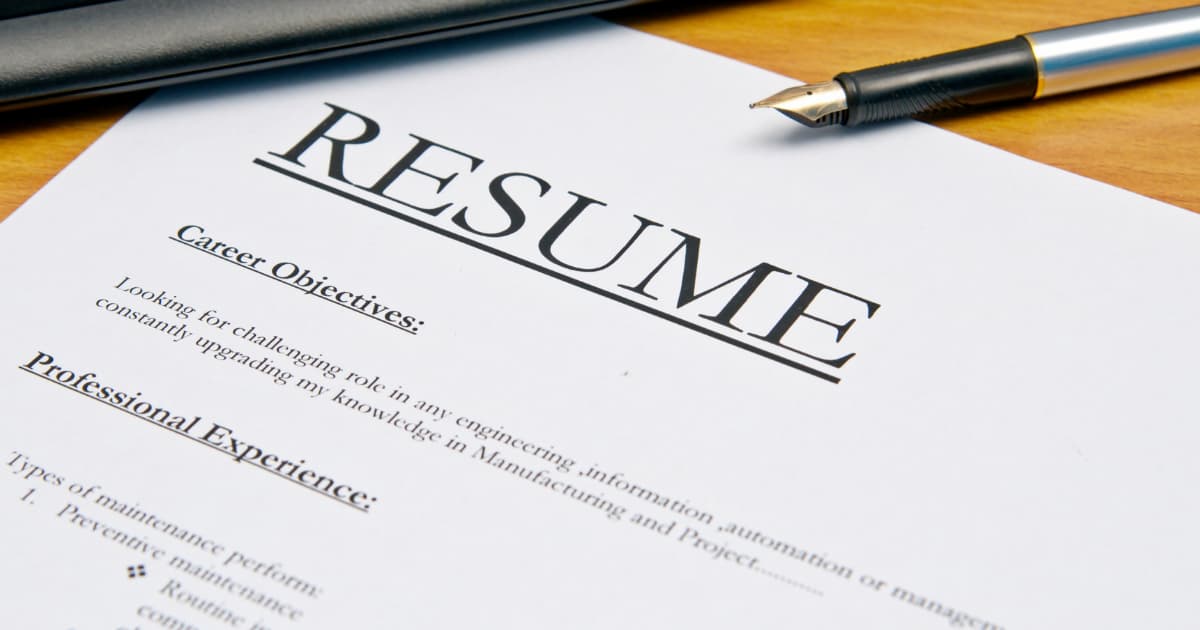 Printed resume document showing the heading ‘Resume,’ with sections for career objectives and professional experience, and a pen resting on the page.