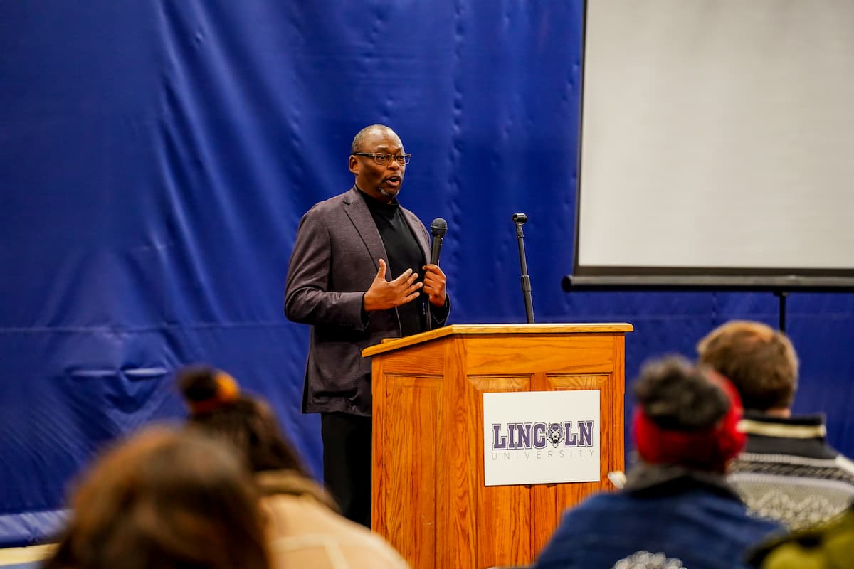 A man stands behind a lectern with a microphone in hand.