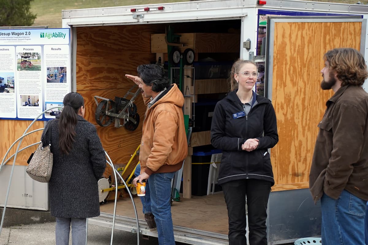 A group of people stands at the open Jesup Wagon 2.0 trailer while a Lincoln University staff member explains tools and equipment inside the mobile classroom.