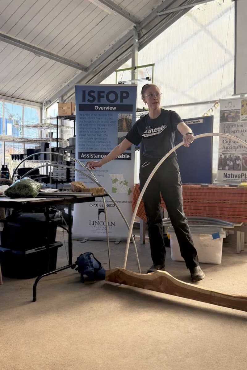 Mary Keeter holds a hoop inside a greenhouse at Finca EcoFarm while speaking about how low tunnels are constructed.