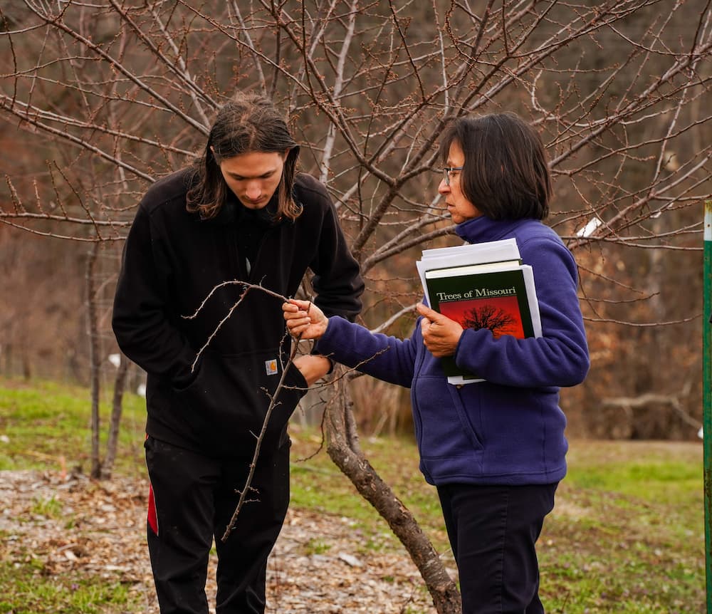 Nadia Navarrete-Tindall stands beside a man and discusses a native fruit tree during the workshop at Busby Farm.