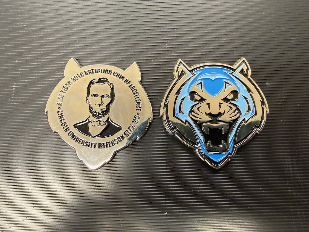 Two ROTC challenge coins lie on a table.