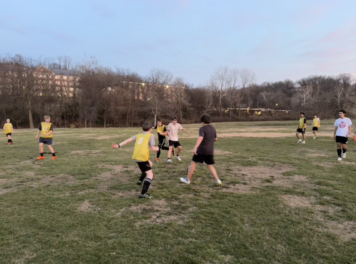 Youth practice soccer on a field outside.