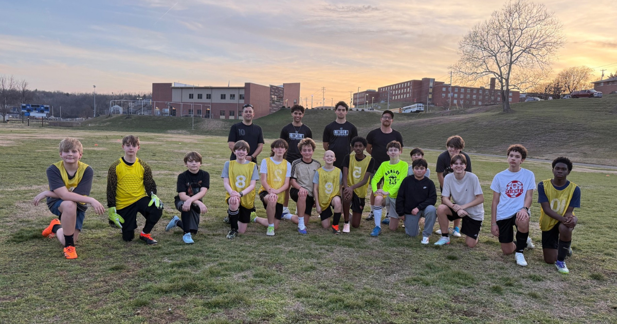  LU soccer players pose for a photo on a soccer field while with young athletes.