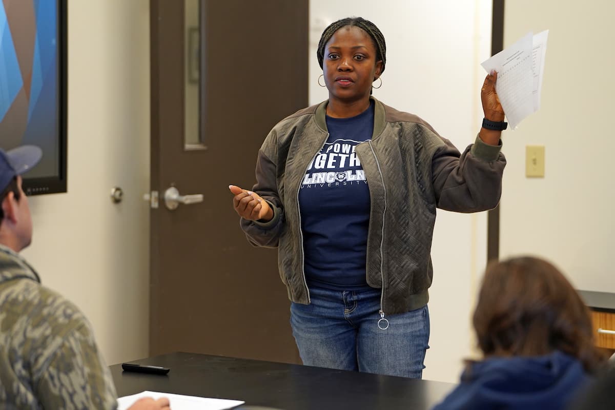 A woman holding a piece of paper up to a group of people.
