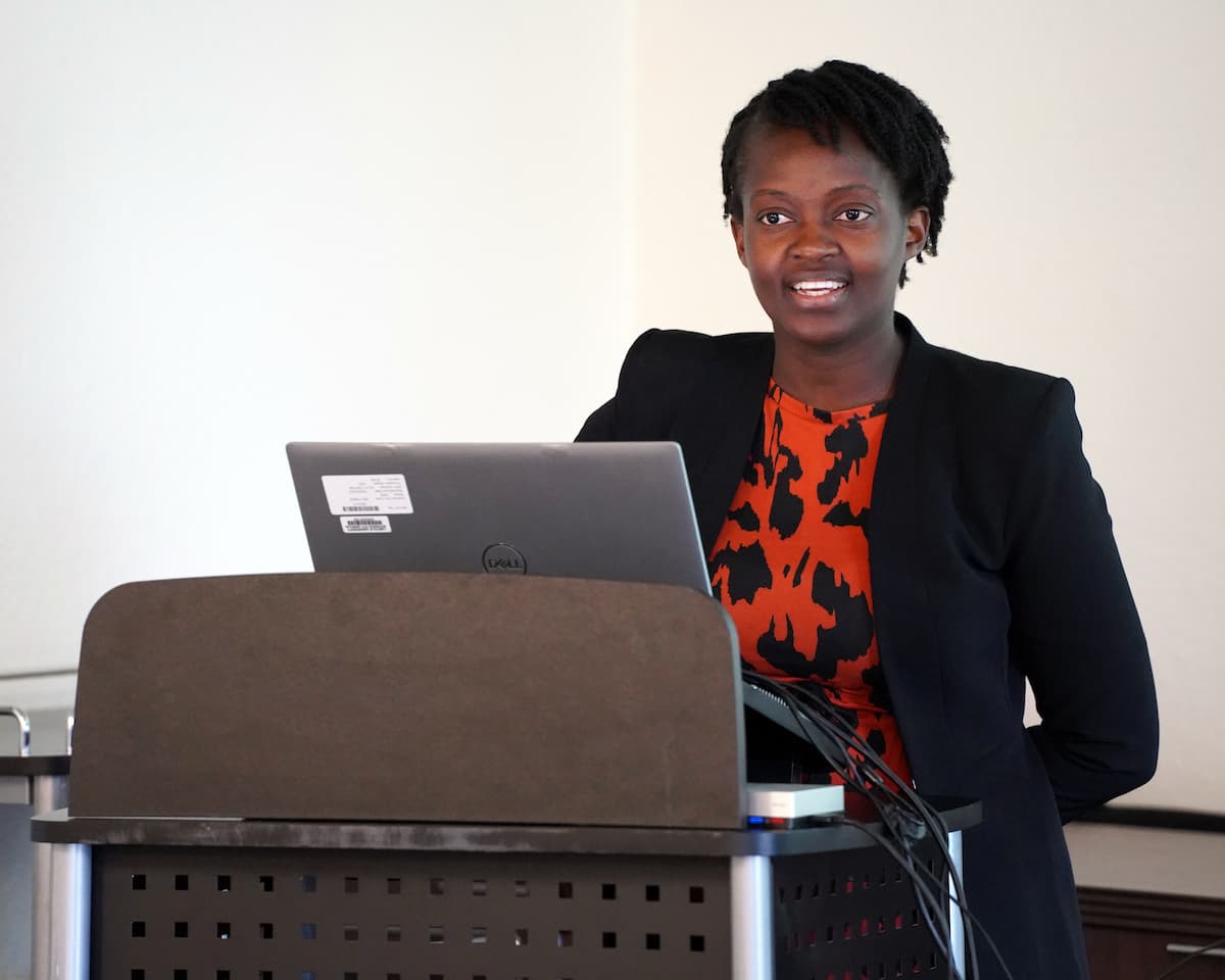 A woman standing at a podium with a laptop on it. 