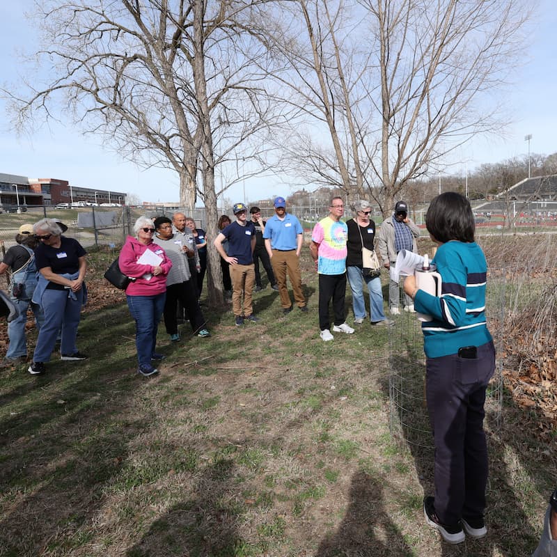 Participants stand outdoors listening to Nadia Navarrete-Tindall, who leads the Native and Specialty Crops Program, during a composting workshop. 