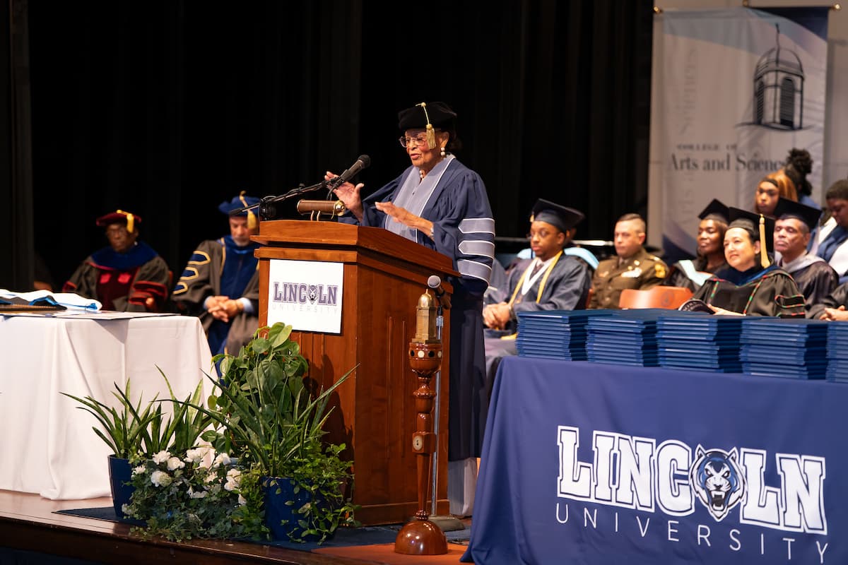 Rep. Adams stands at the podium while giving a graduation speech.