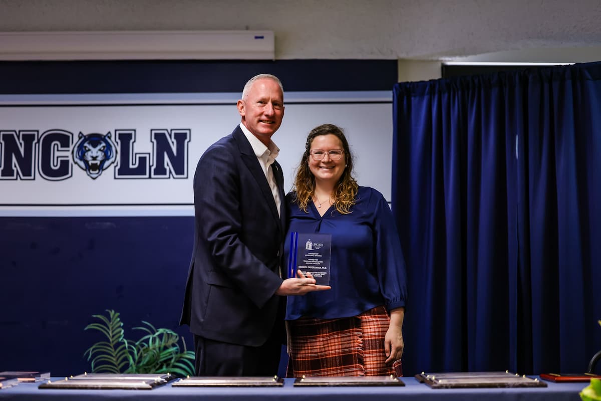 President Moseley and Rachael Pasierowska stand while holding a plaque.