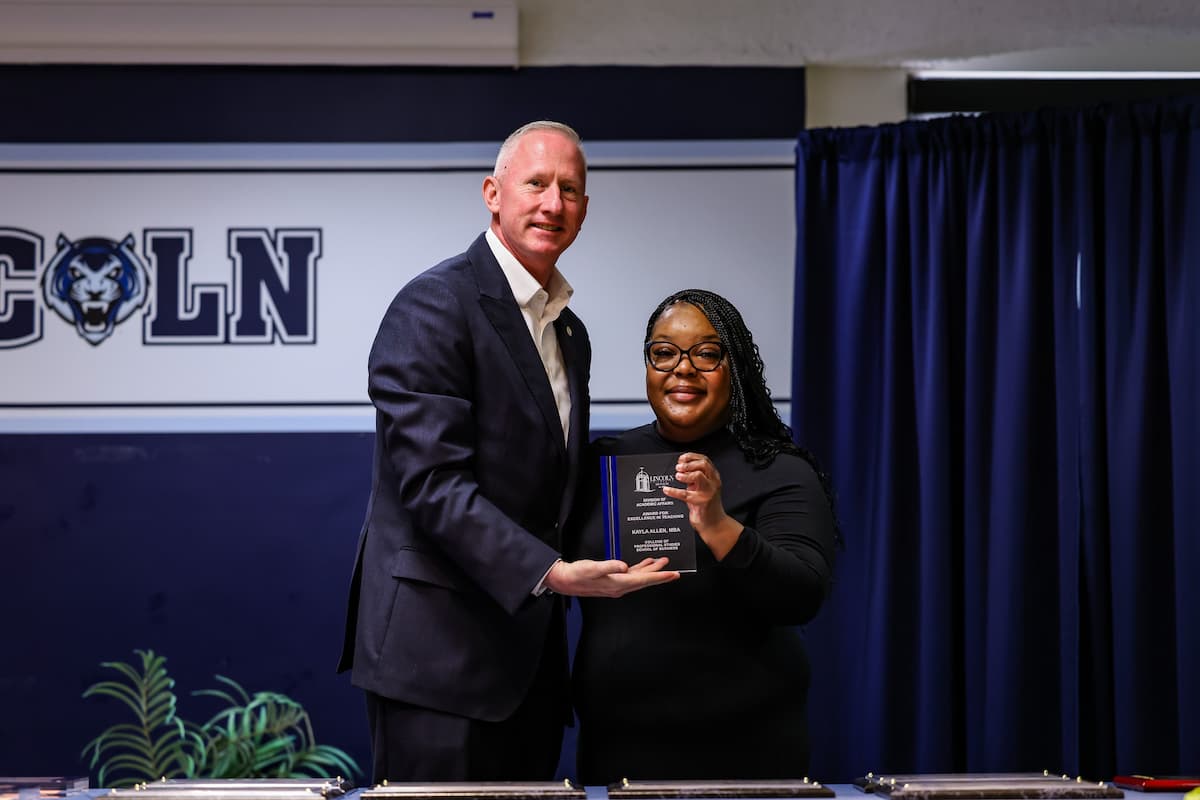 President Moseley and Kayla Allen stand while holding a plaque.
